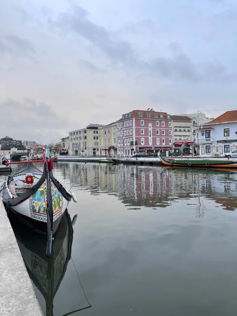 Värvikirev moliceiro paat Aveiro kanalil, pastelsed hooned taustal.
